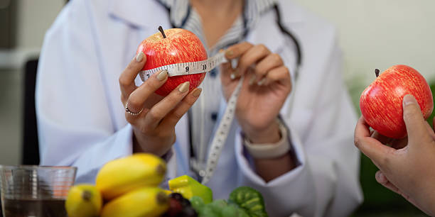 istock Measurement and Nutrition. A nutritionist measures an apple while providing dietary advice to a patient. 2210693671