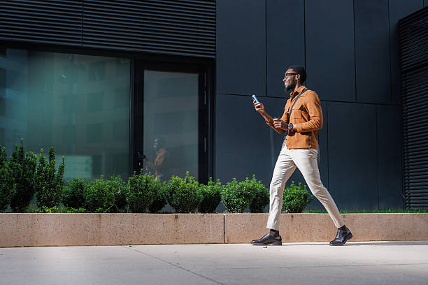 istock A stylish man walk outside a modern building while looking at his phone 2210693726