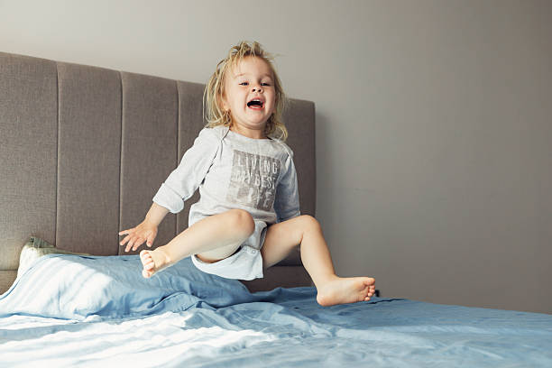 istock Blonde toddler joyfully jumping on bed at home during sunny playtime 2210694006