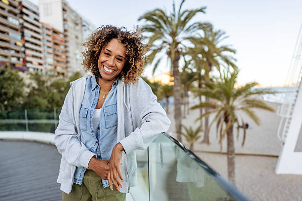 Smiling Woman Relaxing By a Beachfront Promenade With Palm Trees