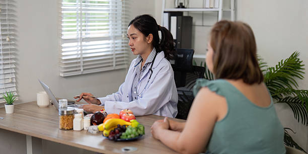 istock Nutritionist and Patient Interaction. A nutritionist works on a laptop during a productive consultation with a client about dietary habits and choices. 2210694408