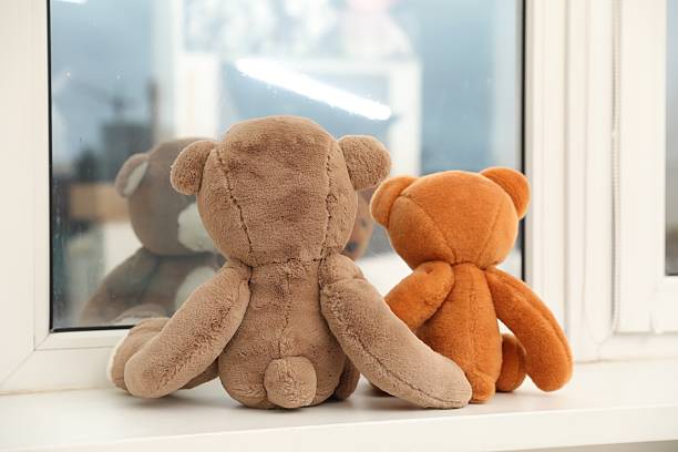 istock Teddy bears on window sill at home, back view 2210695134