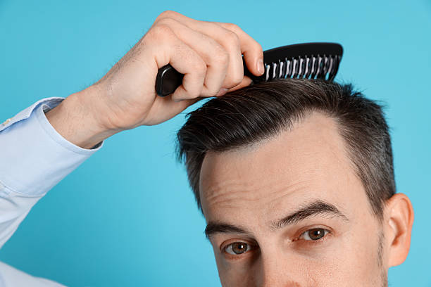 istock Handsome man stylish his hair with comb on light blue background, closeup 2210695849