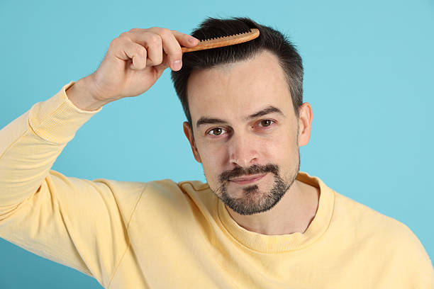 istock Handsome man stylish his hair with comb on light blue background 2210695868