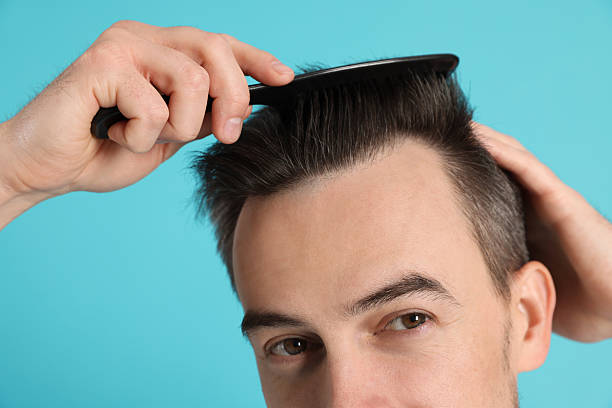 istock Handsome man stylish his hair with comb on light blue background, closeup 2210695872