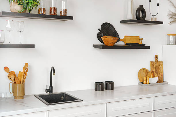 istock Kitchen interior with countertop and black water tap on white wall background with wooden shelves 2210695939