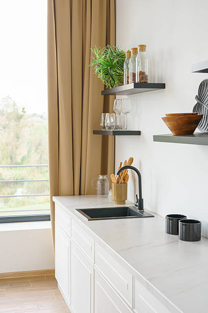 istock Kitchen interior with countertop and black water tap on white wall background with wooden shelves 2210695941