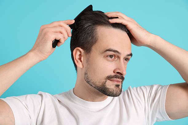 istock Handsome man stylish his hair with comb on light blue background 2210695971