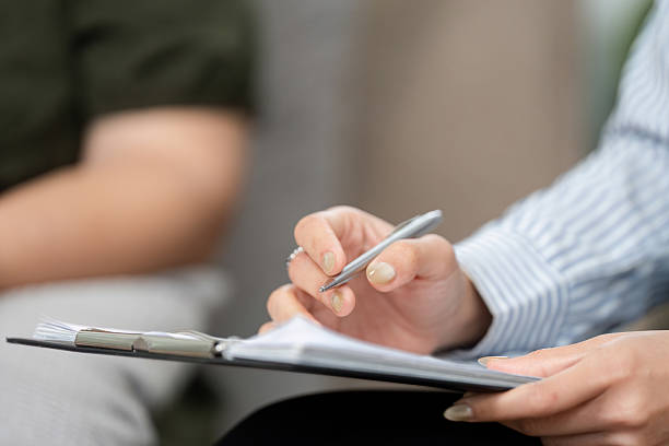 istock Therapeutic Documentation and Engagement. A psychiatrist noting key points during a client session. 2210696560