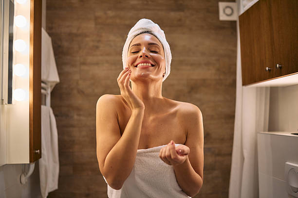 istock Young woman applying moisturizer on face after shower 2210696622