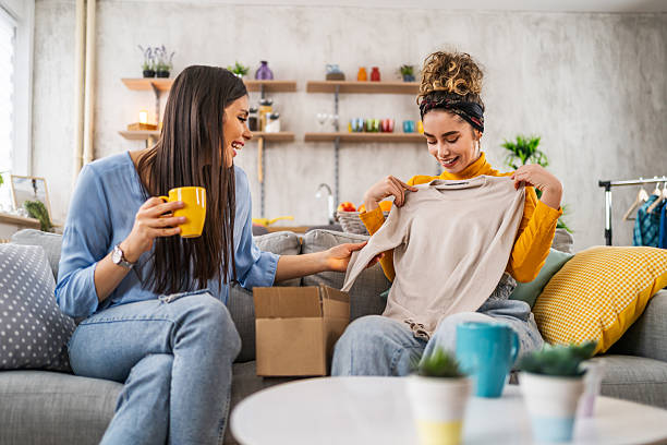 Two young women unpacking clothes from a delivered cardboard box at home