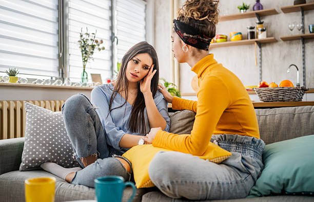 istock Young woman consoling sad friend at home 2210698742