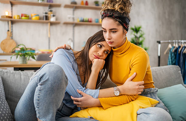 istock Young women embracing and consoling each other on sofa 2210699058