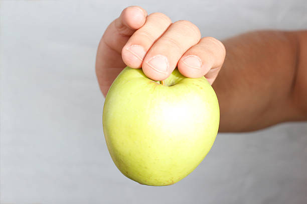 Ripe delicious juicy green apple in hand isolated on white background. Healthy eating and dieting concept