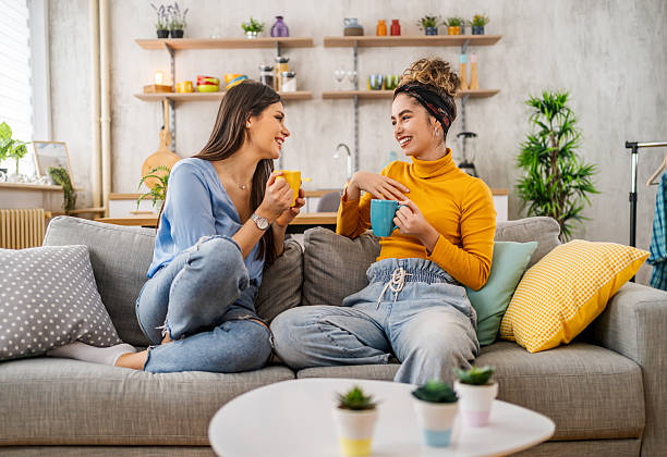 istock Two young women relaxing on sofa, drinking coffee and chatting 2210699444