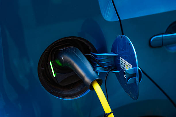 Electric vehicle , Smart car , Air pollution and reduce greenhouse gas emissions concept. Double exposure of charging Electric car with power cable supply plugged in and city night light view.