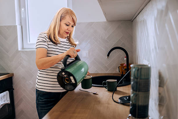 istock Senior woman making coffee in kitchen 2210704858