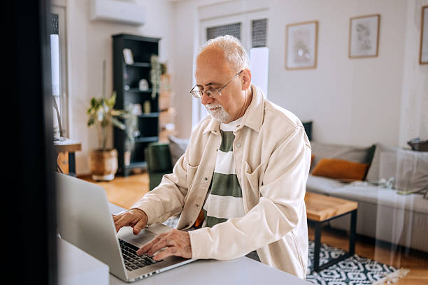 istock A pensioner sits at the dining room table and works on a laptop 2210704986