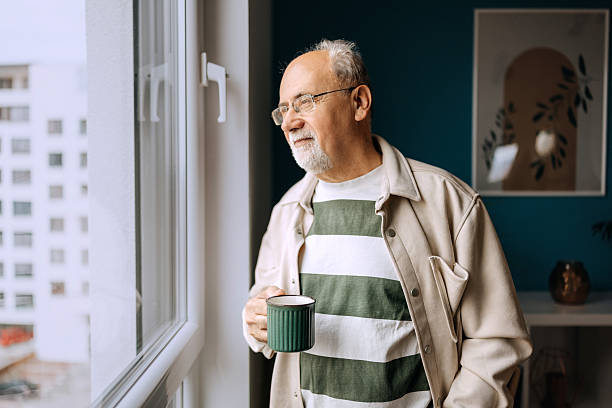 istock Senior man with coffee cup looking out the window 2210705020