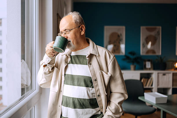 Senior man with coffee cup looking out the window