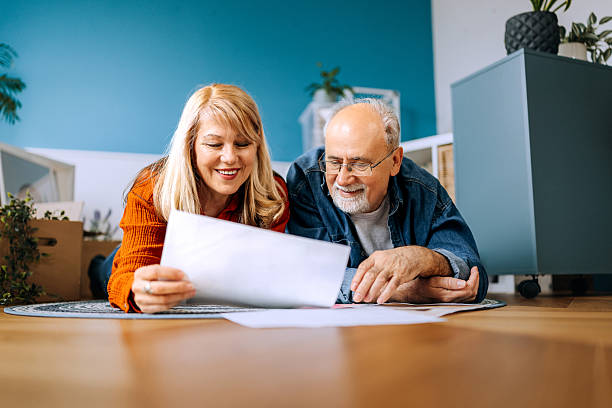 istock Senior couple laying on floor looking document while planning home decor 2210705096