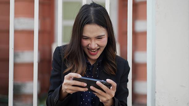 istock asian woman in suit excitedly playing mobile game on smartphone with joyful expression 2210706077
