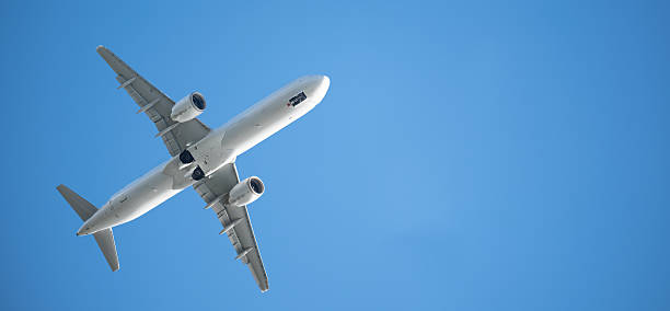 A white A321 passenger plane after take-off, against a bright blue sky. Dynamics and elegance of aviation in action