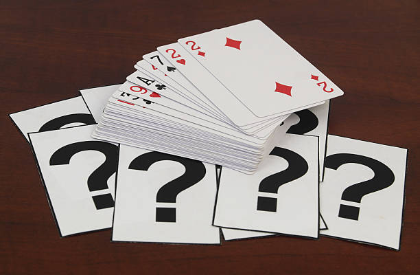 istock Many playing cards and question marks on wooden table close up. 2210708724