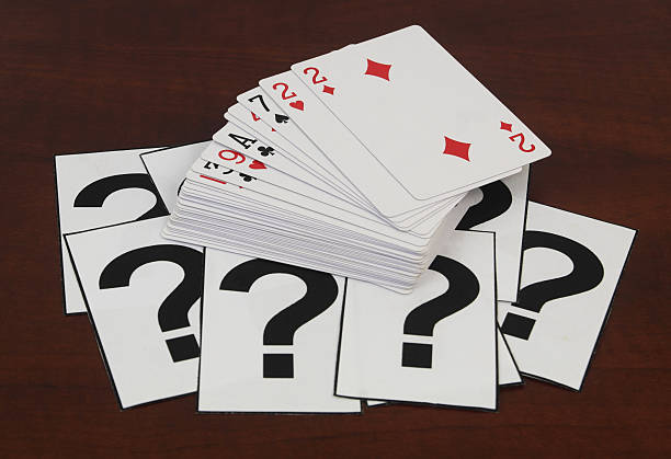 istock Many playing cards and question marks on wooden table close up. 2210709224