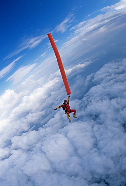 Woman skydiver free falls with streamers (sky tube) above ocean, Hawaii