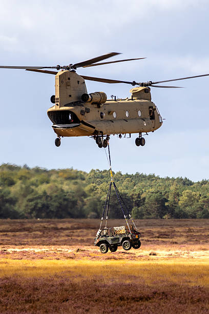 Military all-terrain vehicle slingload transport by  a Boeing CH-47F Chinook helicopter. Ginkelse Heide, The Netherlands - September 17, 2022