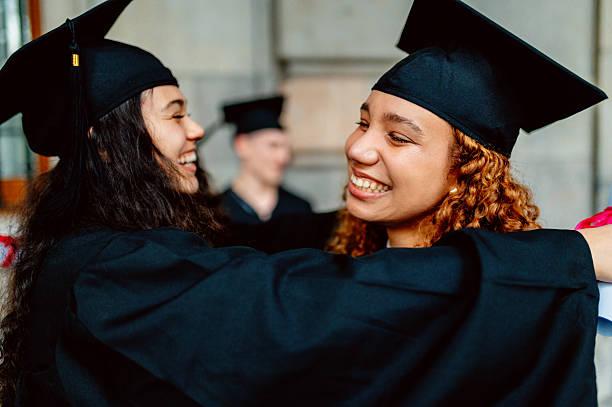 istock Two happy multi ethnic female students hugging at graduation ceremony 2210711811