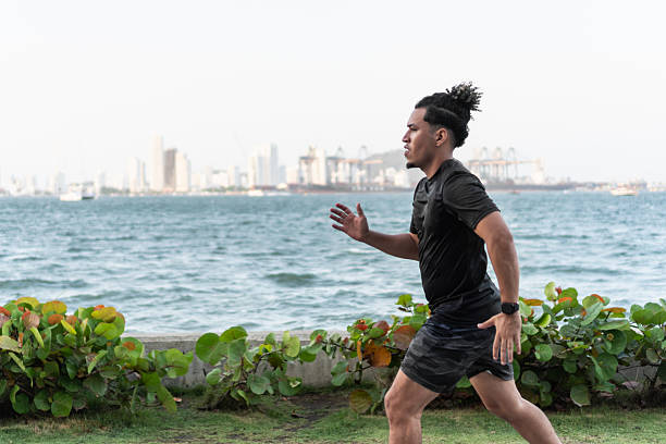 istock Young adult jogging by waterfront cityscape 2210714623