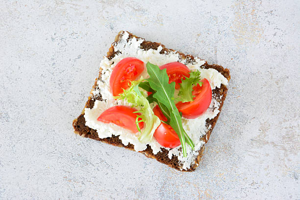 istock Open-faced sandwich with cream cheese, tomatoes and arugula isolated top view 2210714711