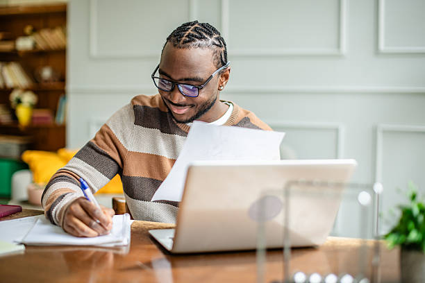 istock Young man engaged in online classes at home while taking notes and enjoying the learning experience 2210714769