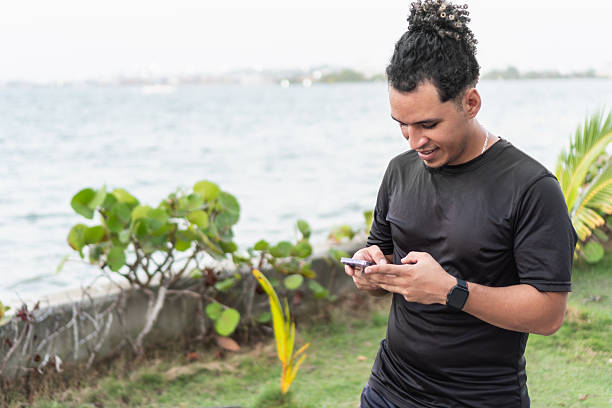 istock Young latino man using smartphone after training by the sea 2210715252