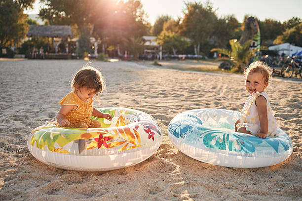 Beautiful twin sisters enjoying sunset on a beach vacation, playing with swimming floats..