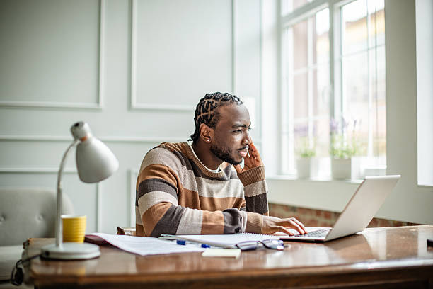 istock Young man engaged in online learning from home using a laptop in a cozy living room setting 2210717299