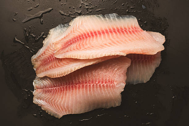 istock Fresh tilapia fillet on black background, top view. 2210720243