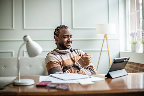 istock Young man enjoys online learning in a bright home office space with a laptop and study materials 2210720342