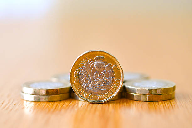 istock Single British one pound coin standing on its edge with other coins 2210725506