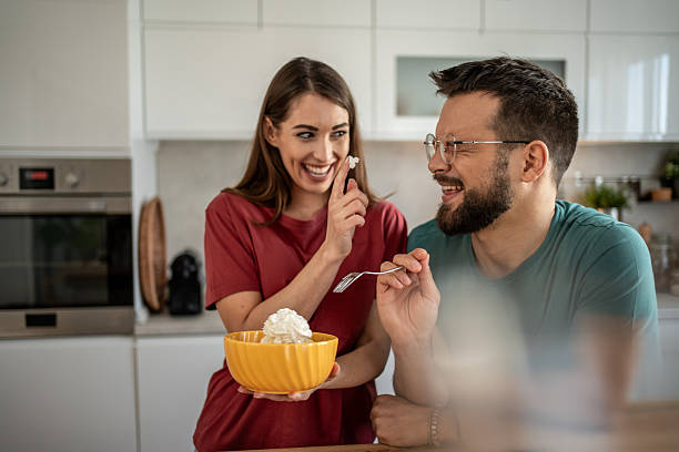 istock Playful couple sharing whipped cream in the kitchen 2210725782