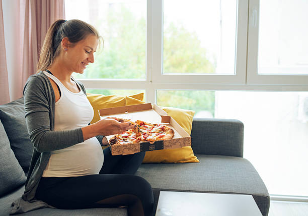 istock Pregnant woman eating pizza. 2210726438