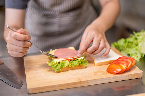 istock Smiling Young Female Chef Preparing a Sandwich in a Professional Kitchen 2210728492