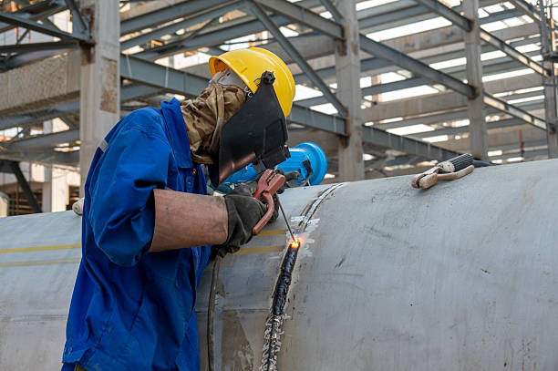 A worker is welding steel pipes at a construction site