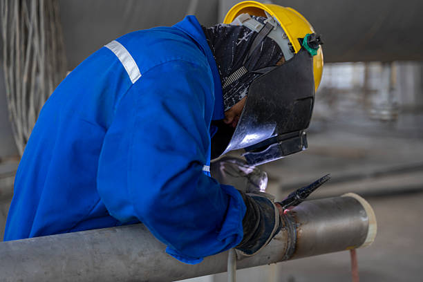 A worker is welding steel pipes at a construction site