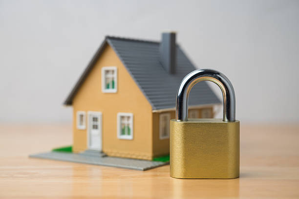 istock Padlock and house model on wooden table with white wall background. 2210748445
