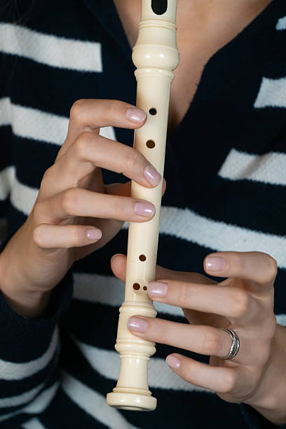 istock Female musician skillfully playing a recorder flute, demonstrating precise finger placement and creating beautiful music with her instrument. Vertical photo 2210752029