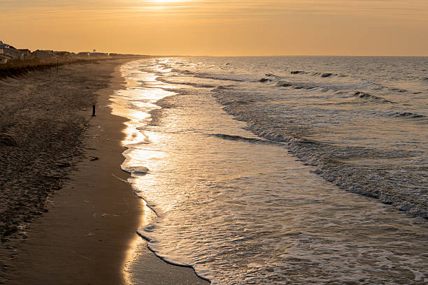 Golden morning sunlight reflects off gentle waves along the quiet Oak Island beach in North Carolina.