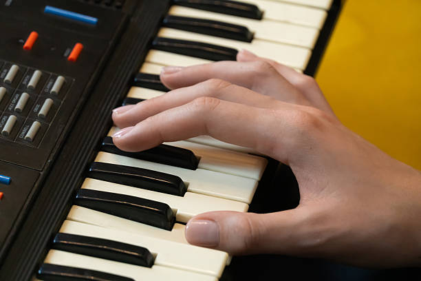 istock Capturing the essence of creativity, musician's hands skillfully playing a vintage synthesizer keyboard, generating electronic music against a vibrant yellow backdrop 2210754465